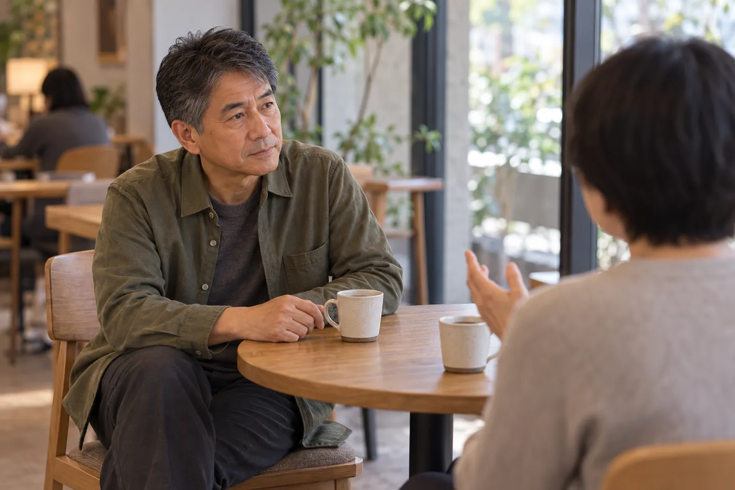 テーブルを挟み、相手の話を聞く男性